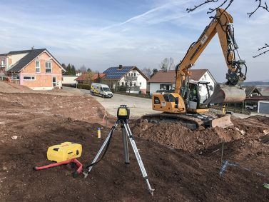 Messgerät und Kettenbagger beim Strassenbau